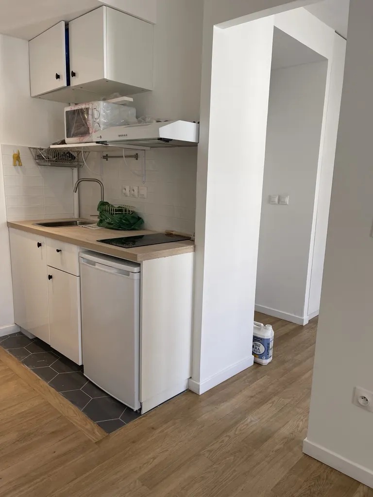 Cuisine compacte avec meubles blancs, plan de travail aspect bois et crédence en carreaux blancs